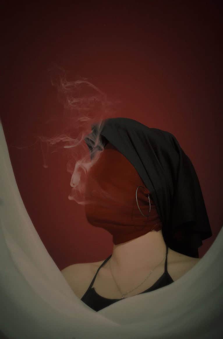 woman with a wrapped head smoking a cigarette
